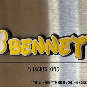 A yellow and black custom name magnet with the name 'BENNETT' in a mouse inspired font. This magnet example is 5 inches long and includes a Mouse head design on the left of the name. *Magnets will vary on length depending on name length.