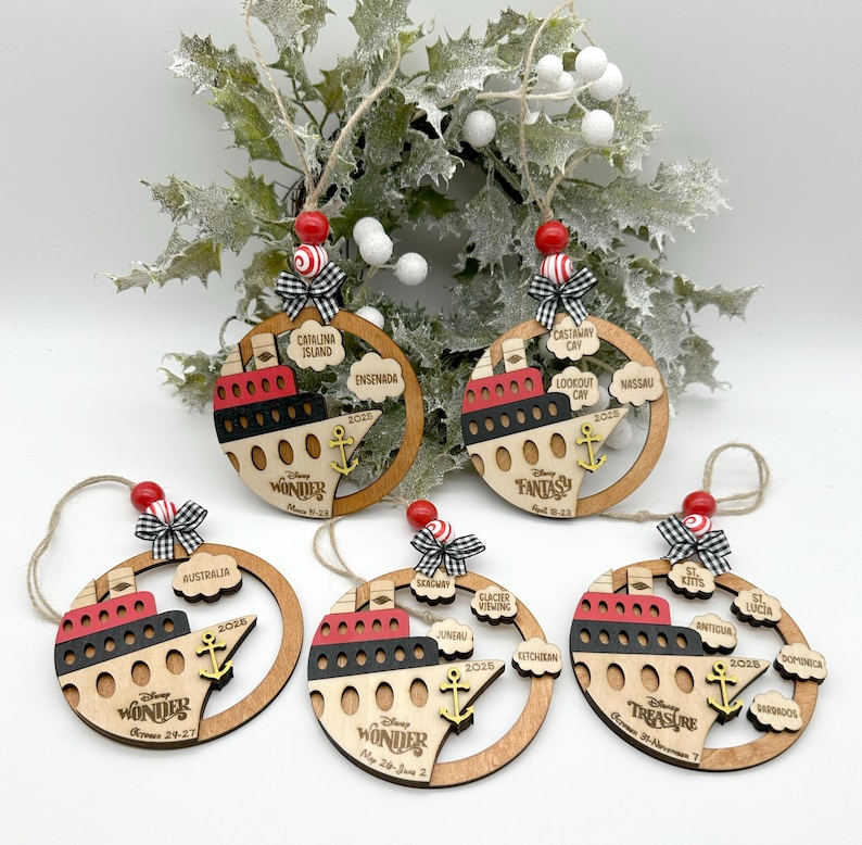 A set of 5 wooden ornaments with a boat image painted in red, black and natural wood colors. The boat features a DCL ship logo, dates of the cruise and the DCL logo. It also has a anchor painted in yellow on top of the boat. The ornaments have clouds on the right side with port locations. The ornament comes with between 1-5 port location clouds. All ornaments have 2 colored wood beads, a black and white mini fabric bow and twine for hanging on top of the ornament.