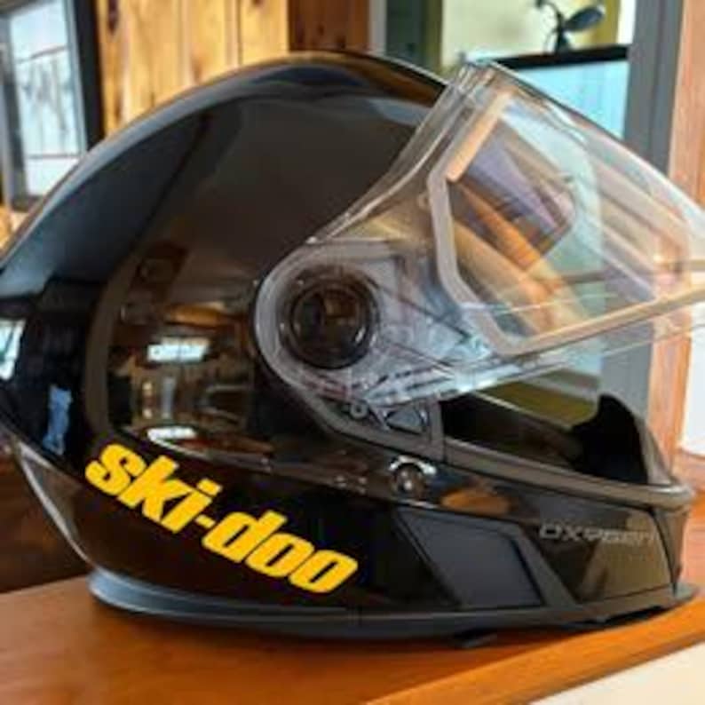 May include: Black ski helmet with a clear visor and a yellow "ski-doo" decal on the side.