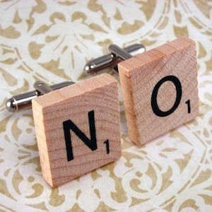 May include: A pair of wooden cufflinks with the letters "N" and "O" on them. The letters are from a Scrabble game and have the number "1" on them.