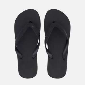 May include: A pair of black flip-flops. The flip-flops have a simple design with a single strap.