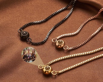 May include: Three adjustable bracelets with a small round charm that can hold a photo. The charms are black, rose gold, and gold. The bracelets are on a brown fabric background.