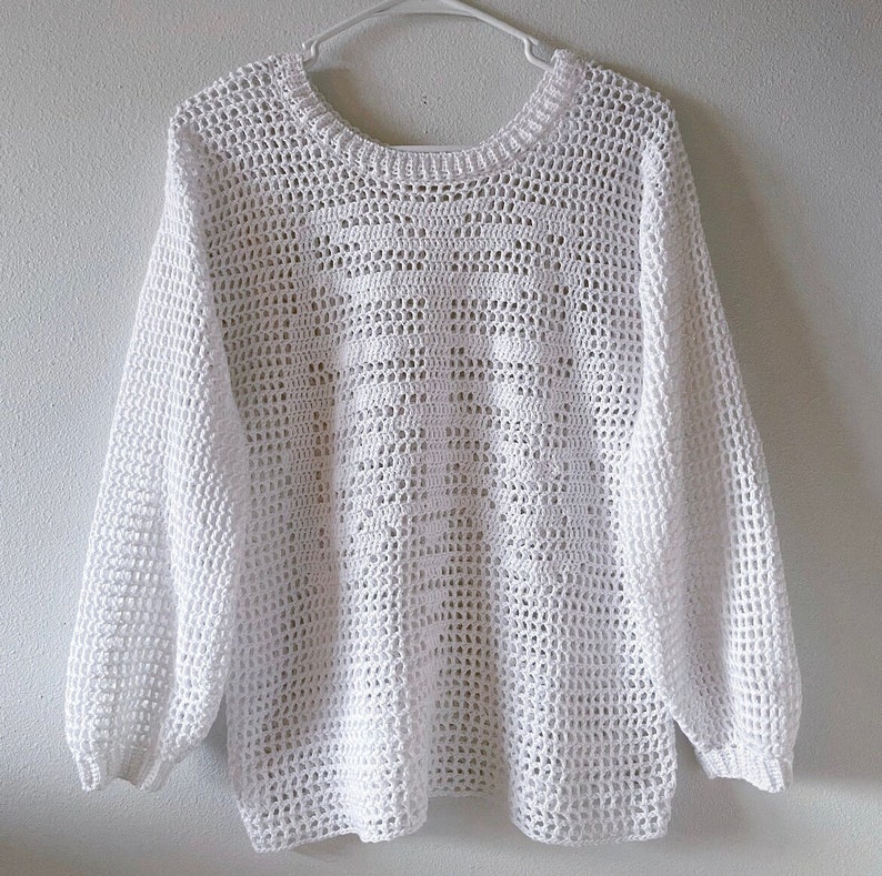 Puede incluir: Su&eacute;ter blanco de ganchillo con un corte holgado y mangas largas. El su&eacute;ter tiene un delicado patr&oacute;n de calado.