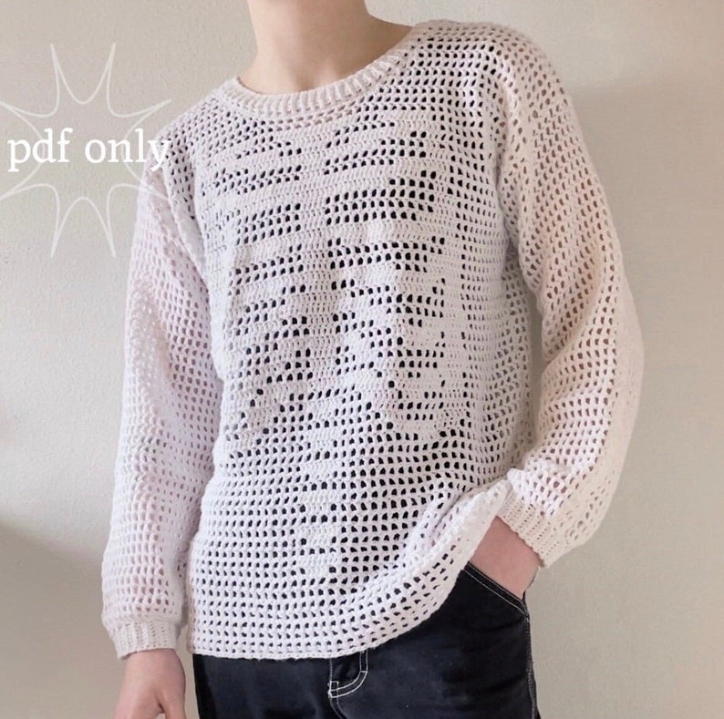 Puede incluir: Su&eacute;ter de crochet blanco con un patr&oacute;n geom&eacute;trico. El su&eacute;ter tiene mangas largas y un cuello redondo.