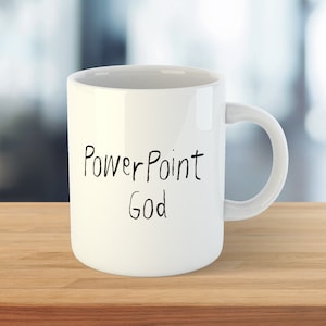 Könnte beinhalten: Weiße Keramik-Kaffeetasse mit schwarzem handgeschriebenem Text, der "PowerPoint God" lautet.