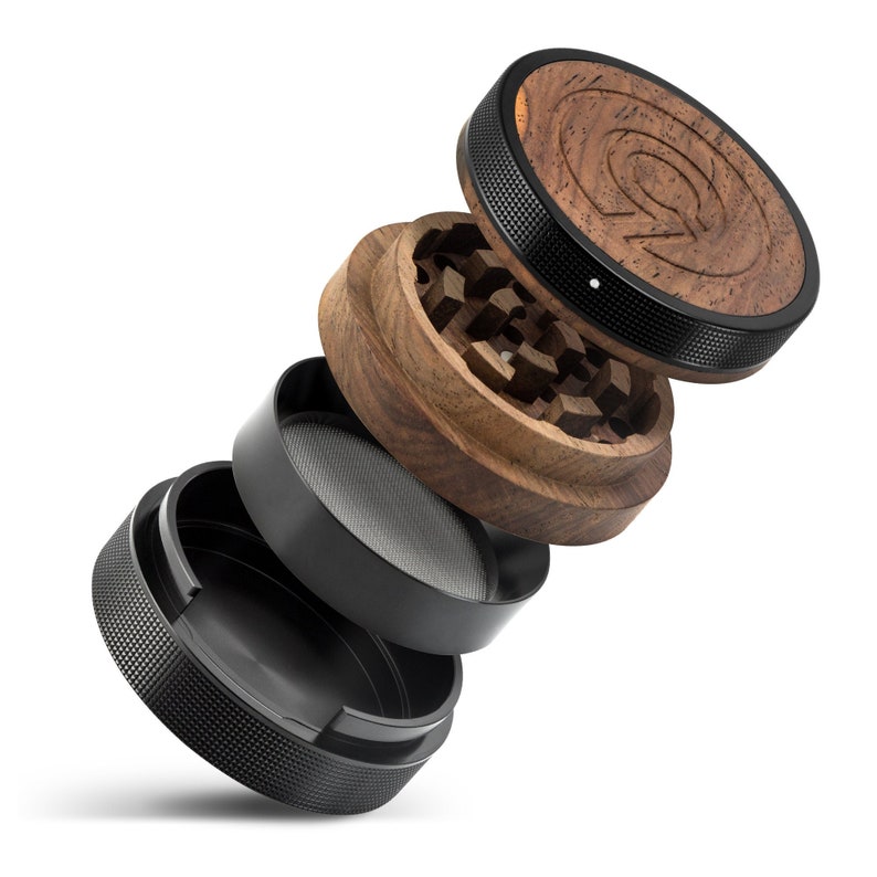 May include: A disassembled wooden and metal grinder with a black metal base, a black metal screen, a wooden grinder with a black metal ring, and a wooden top with a black metal ring and a logo.
