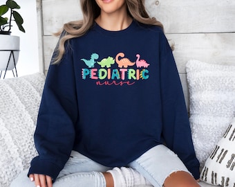 May include: A navy blue sweatshirt with a colorful dinosaur graphic and the text "PEDIATRIC nurse".