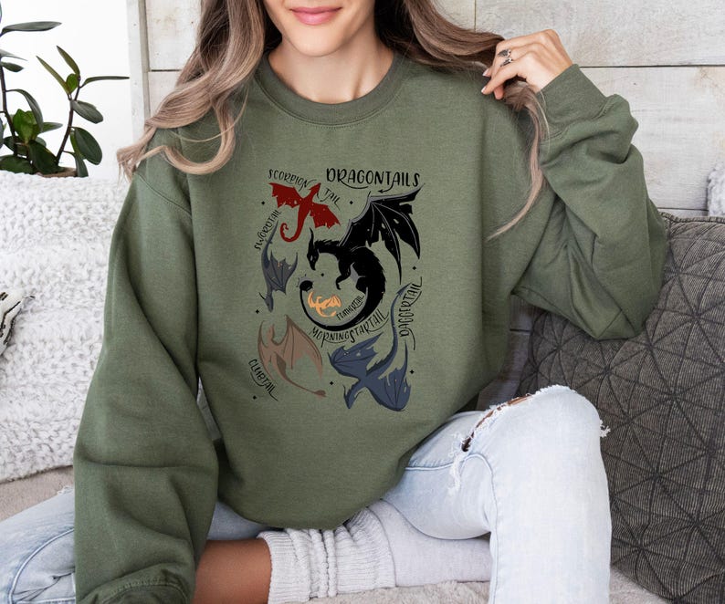 May include: A green sweatshirt with a graphic of five dragons with different names: "Scorpion Tail", "Embertail", "Morning Startail", "Thunder", and "Dragontail".