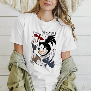 May include: White t-shirt with a graphic of different dragon tails. The tails are labeled with names like "Scorpion Tail", "Morningstar Tail", and "Daggertail".