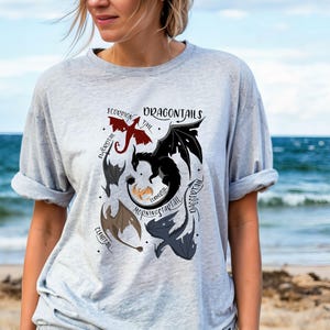 May include: A grey t-shirt with a graphic of different dragon tails labeled with their names: "Scorpion Tail", "Firegreath", "Doggcertail", "Morningstarttail", "Fearless", "Clubtail".