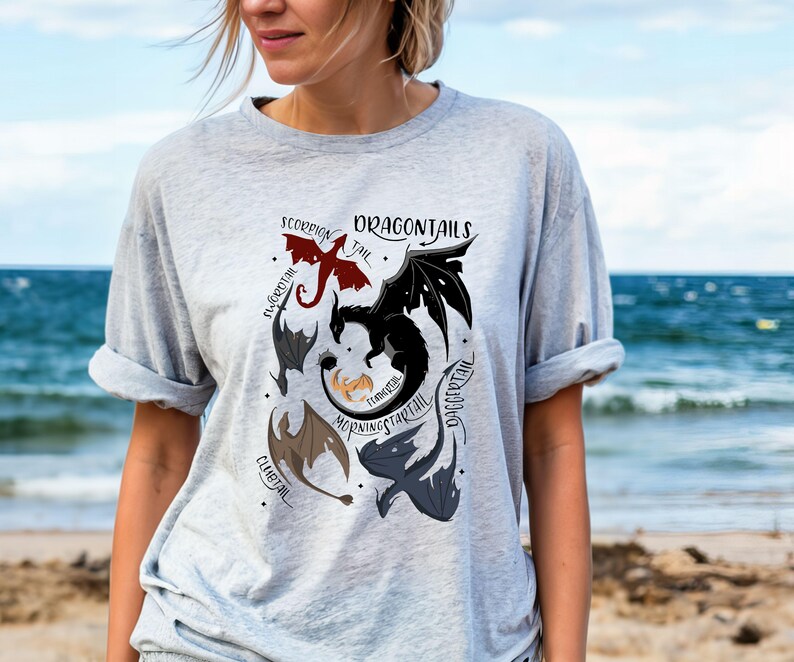 May include: A grey t-shirt with a graphic of different dragon tails labeled with their names: "Scorpion Tail", "Firegreath", "Doggcertail", "Morningstarttail", "Fearless", "Clubtail".