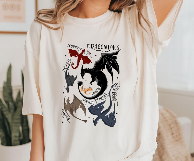 May include: White t-shirt with a graphic of different dragon tails. The tails are labeled with names like "Dragontail", "Morningstarttail", "Daggertail", "Flametail", "Clubtail", "Scorpian Tail", and "Icecrystal".