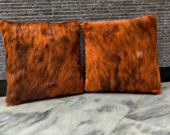 May include: Two orange and black cowhide throw pillows with a soft, fuzzy texture.