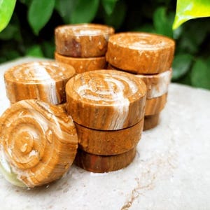 May include: A collection of small, round, wooden objects with a natural, swirled grain pattern in shades of brown and white. The objects are stacked in small piles, suggesting a decorative or functional purpose. The wood has a polished appearance.