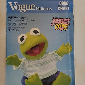 May include: A vintage Vogue Patterns craft pattern featuring a Muppet Babies soft sculpture of Kermit the Frog. The pattern includes instructions for creating the frog's body, clothes, and facial features. The pattern is from 1984.