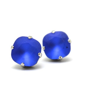 May include: A pair of small, square-shaped earrings with blue crystal stones set in silver.