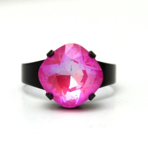 May include: A black ring with a large, pink, faceted gemstone.