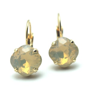 May include: A pair of gold earrings with a light brown, faceted, round crystal.