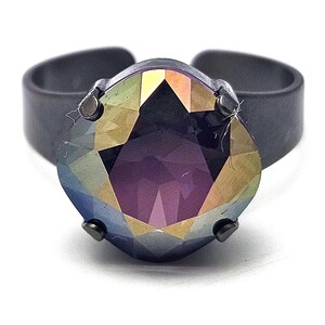 May include: A dark grey adjustable ring with a large, faceted, iridescent gemstone. The gemstone displays a spectrum of colours, including purple, gold, and blue. The ring's band is a simple, minimalist design.