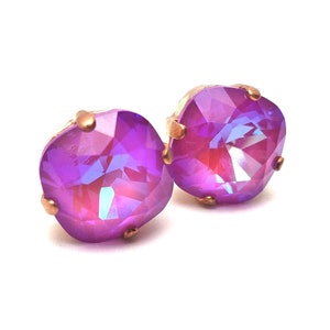 May include: A pair of iridescent purple stud earrings with a rose gold setting.