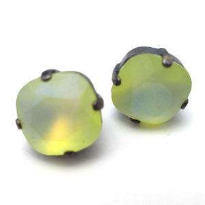 May include: A pair of earrings with a light green, iridescent stone set in a silver tone metal setting.