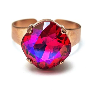 May include: A rose gold ring with a large, faceted, red and purple gemstone.