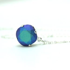 May include: A silver chain necklace with a large, round, iridescent blue and green gemstone pendant.