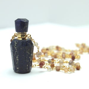 Könnte beinhalten: Eine goldene Kettenkette mit einem Anhänger aus Lapislazuli-Edelstein. Die Kette ist aus Gold und hat kleine Edelsteinperlen.