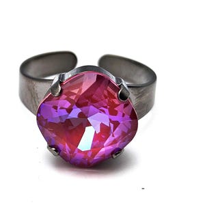 May include: A silver ring featuring a large, faceted, pink and purple gemstone.