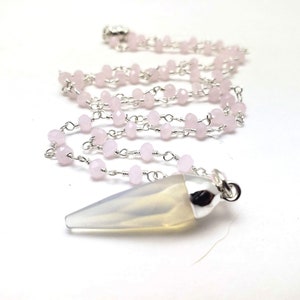 May include: A silver chain necklace with a clear quartz crystal pendant and pink beads.