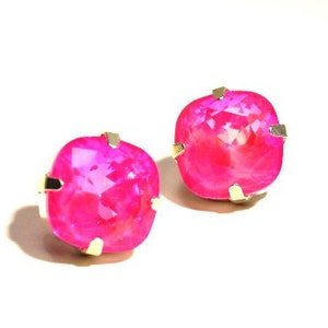 May include: A pair of pink square-shaped earrings with gold settings. The earrings are made of crystal.