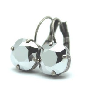 May include: A pair of silver-toned leverback earrings. Each earring features a large, faceted, round, light gray crystal. The crystals are set in a silver-colored metal setting. The earrings are displayed against a white background.