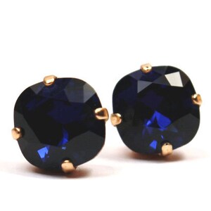 May include: A pair of gold stud earrings with dark blue square-shaped gemstones.