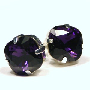 Puede incluir: Un par de pendientes de botón de plata con piedras cuadradas de color morado oscuro.