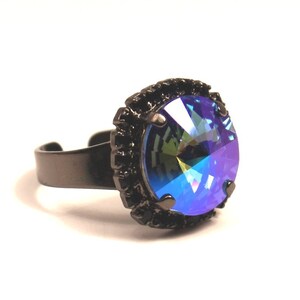 May include: A black ring with a large, round, iridescent blue gemstone set in a black metal bezel.