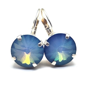 May include: A pair of leverback earrings with large, round, faceted blue crystals. The crystals have a color-shifting effect, with hints of yellow and green. The earrings are set in silver-colored metal.