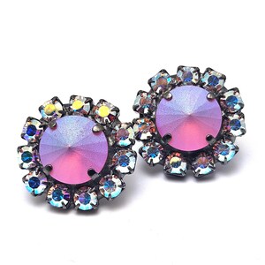 May include: A pair of iridescent pink earrings with a round, faceted crystal center surrounded by smaller crystals.
