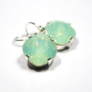 May include: A pair of silver dangle earrings with light green square-shaped stones.