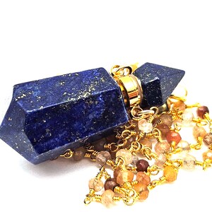 Könnte beinhalten: Eine goldene Kettenkette mit einem lapislazuli Anhänger in Form einer Flasche. Der Anhänger hat einen goldenen Verschluss und ist von kleinen, mehrfarbigen Edelsteinperlen umgeben.