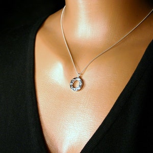 May include: A silver chain necklace with a textured silver circle pendant.