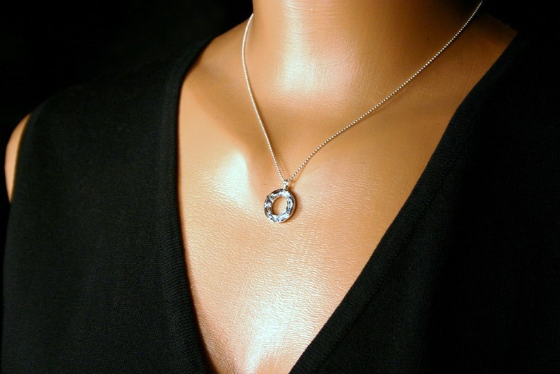 May include: A silver chain necklace with a textured silver circle pendant.