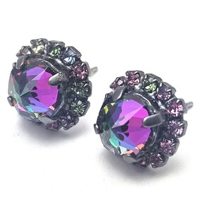 May include: A pair of black stud earrings with a large iridescent purple gemstone surrounded by a halo of smaller multi-colored gemstones.