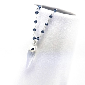 May include: A silver necklace featuring a pendant with a light blue, pointed design. The necklace has a delicate chain with small, dark blue beads. The pendant is a light blue color with a silver cap.