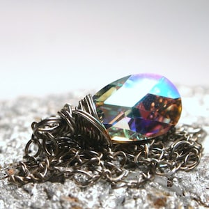 May include: A silver chain necklace with a large iridescent crystal pendant. The crystal is faceted and has a rainbow of colors.