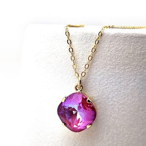 May include: A gold chain necklace with a large, square-shaped, pink crystal pendant.
