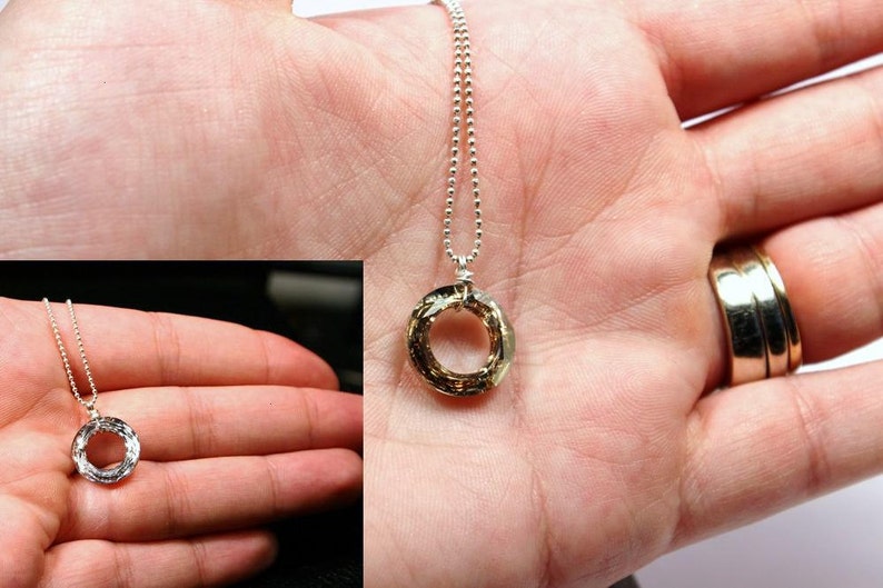 May include: A silver chain necklace with a gold-toned pendant. The pendant is a circle with a textured surface.
