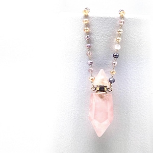 May include: A pink crystal pendant necklace with a gold chain and a clear glass bottle stopper. The chain is made of small, multi-colored beads.