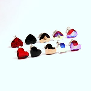 May include: Assortment of heart-shaped earrings in various colors, including red, black, gold, and iridescent. The earrings are made of metal and have a stud back.