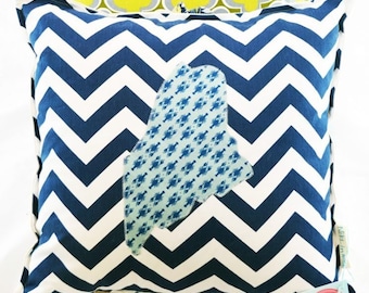 May include: A blue and white chevron patterned pillow with a light blue applique of the state of Maine, featuring a pattern of small blue lobsters. The pillow has a tag that says "Nikki-Lynn Jewelry".