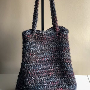 May include: A black, gray, and red crocheted tote bag with two long straps.